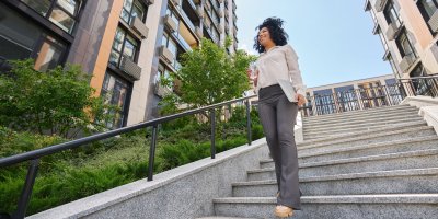 Woman walking down the stairs smiling surrounded by tall buildings