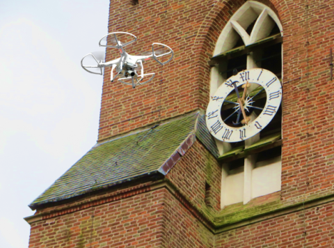 Drone flying in front of a church clock.