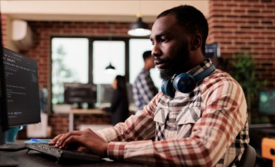 Man in workplace working on his laptop from the side