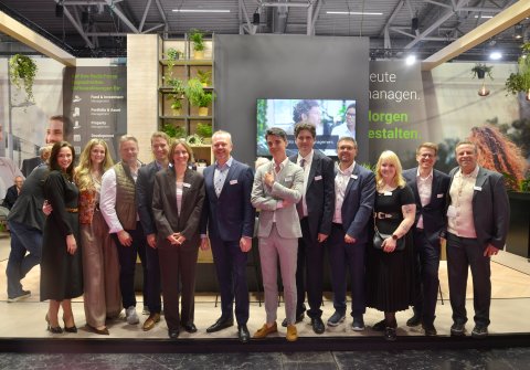Group photo of the Planon Real Estate team standing in front of the exhibition stand at EXPO REAL 2026.
