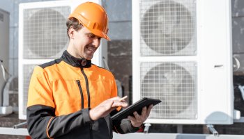Maintenance worker checking air conditioning data on a tablet.