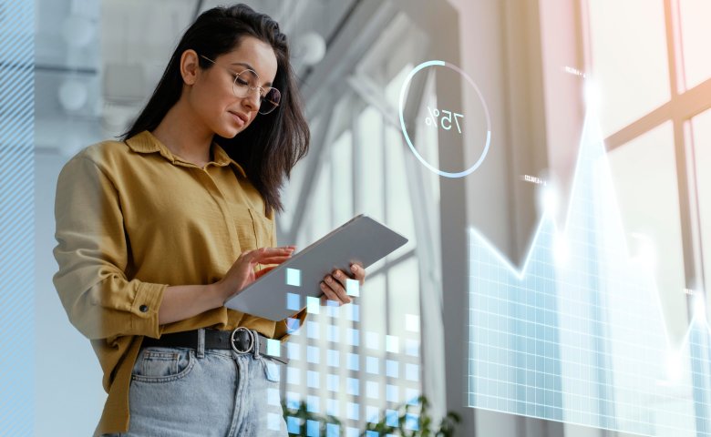 Woman using a tablet in a bright office with digital charts