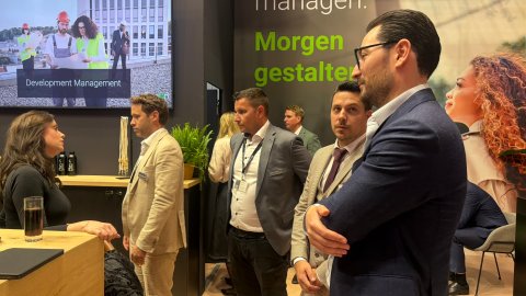 Networking event at the Planon Real Estate stand with attendees meeting around the hospitality area.