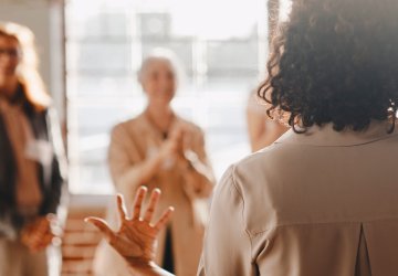 The back of a woman speaking to a group of people
