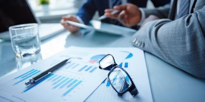 Business meeting with documents, charts, and glasses on a desk.