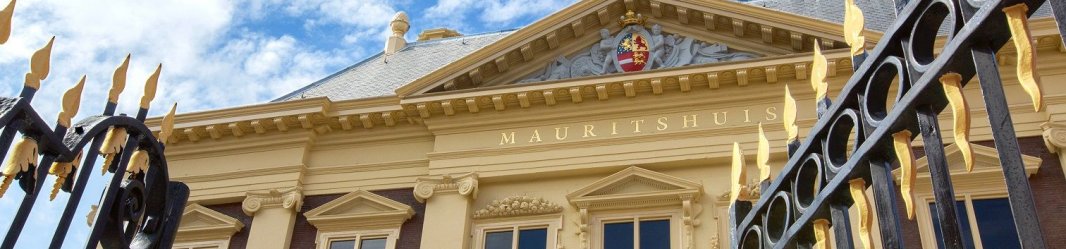 Mauritshuis museum building with golden accents and a decorative gate under a blue sky.