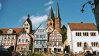 Charming houses with traditional architecture and church towers under a bright sky.