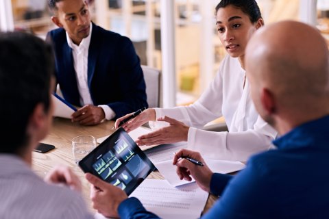 Group of colleagues in business meeting discussing facility data on a tablet