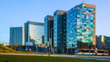 Glass midrise office building with colorful windows reflecting the sky.