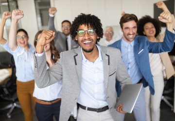 Group of co-workers cheering for a great working environment.