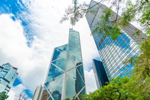 Modern skyscraper in Hong Kong, showcasing sleek architecture with glass facades reflecting the vibrant cityscape.