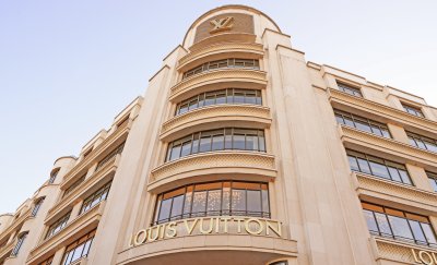 Low-angle shot of the Louis Vuitton building, featuring its beige facade and gold branding.