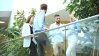 Young people brainstorming while standing against a glass railing.