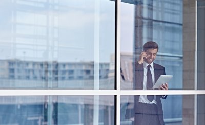 Man on the phone holding iPad in workspace