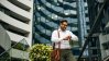 Business man looking at his watch in front of real estate buildings