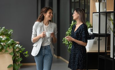 Two women drinking coffee in the office.