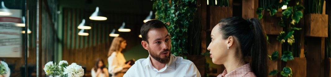 People discussing a plan while sitting on a table with an open laptop.