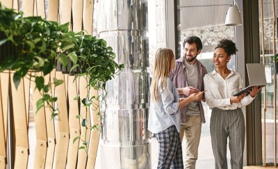 Group collaborating in modern office with plants, laptop and notes.