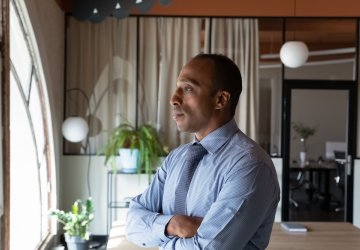 Thoughtful young African-American businessman looking through a window.