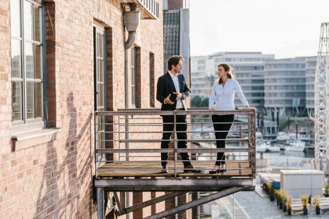 Business people talking on balcony with real estate buildings 