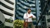 Business man looking at his watch in front of real estate buildings