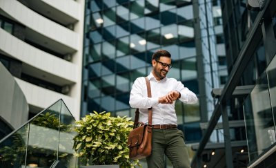 Business man looking at his watch in front of real estate buildings