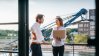 Two business professionals standing on a balcony, engaged in a thoughtful discussion, with a city skyline in the background.