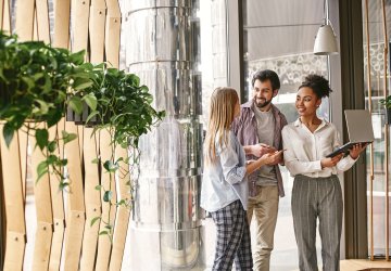 Group collaborating in modern office with plants, laptop and notes.
