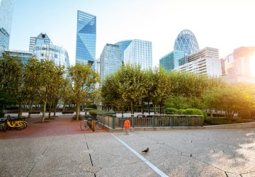 Tall skyscrapers at financial district of Paris with green parking lot in front.