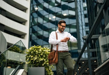 Business man looking at his watch in front of real estate buildings