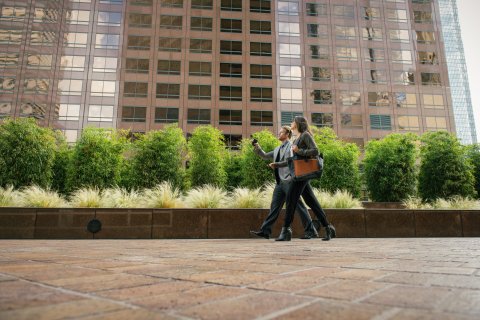 Businesspeople walking outside an office building, engaging in a conversation.