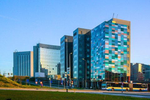 Glass midrise office building with colorful windows reflecting the sky.