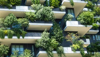 Trees and plants growing on balconies of a building as a green facade or vertical garden.