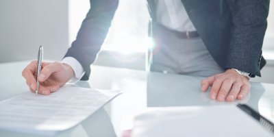 Man signing a document on a desk.
