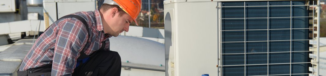 Worker fixing air conditioning on a roof