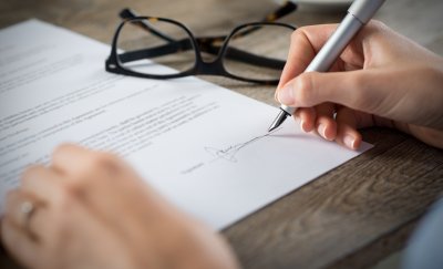 Women signing a document on a desk