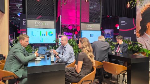 Visitors reviewing software dashboards and analytics displayed on screens during a meeting.