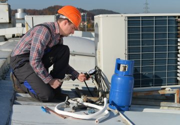 Worker fixing air conditioning on a roof