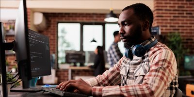 Man in workplace working on his laptop from the side