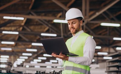 Young engineer with helmet looking at laptop.