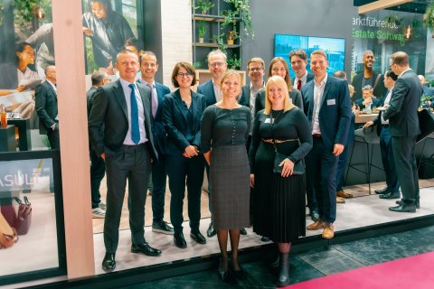 Group of people standing side by side for a photo at an exhibition booth.