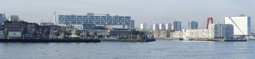 Distant cityscape with modern buildings and water in the foreground, under a clear sky.