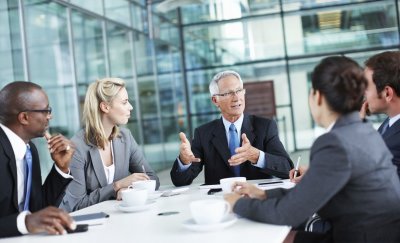 Business people gathering and discussing around a table in a meeting room.