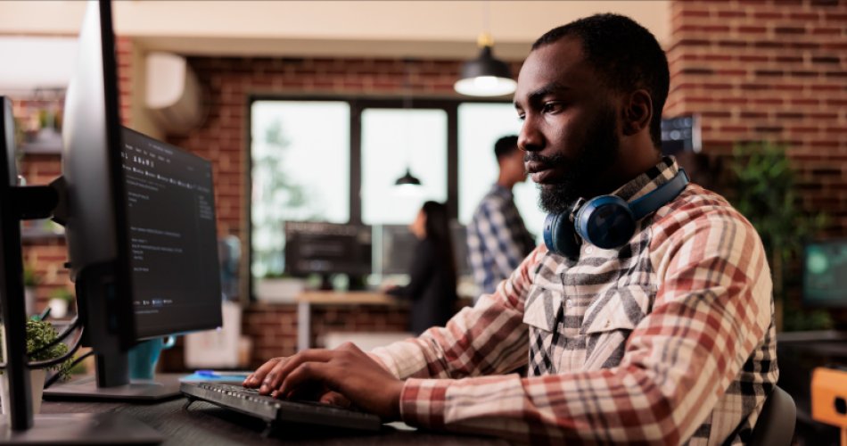 Man in workplace working on his laptop from the side