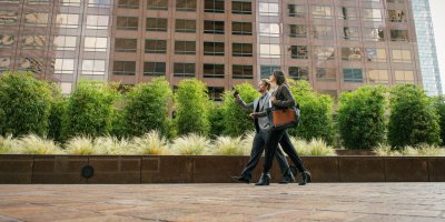 Businesspeople walking outside an office building, engaging in a conversation.