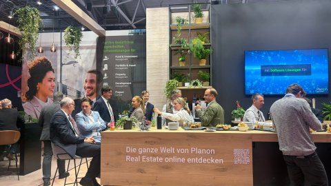Visitors and exhibitors gathered around the catering area at the Planon Real Estate stand.