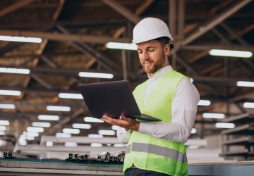 Young engineer with helmet looking at laptop.
