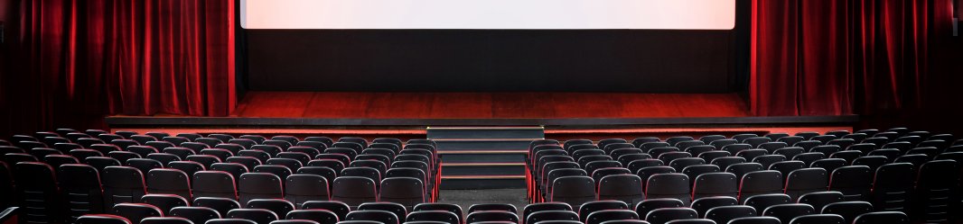 Empty filmtheatre with red curtains and white screen