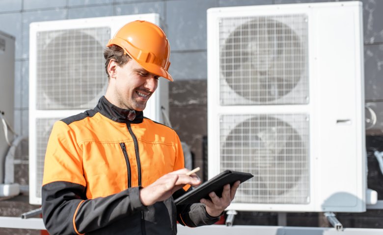 Maintenance worker checking air conditioning data on a tablet.