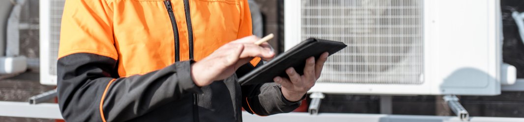 Maintenance worker checking air conditioning data on a tablet.